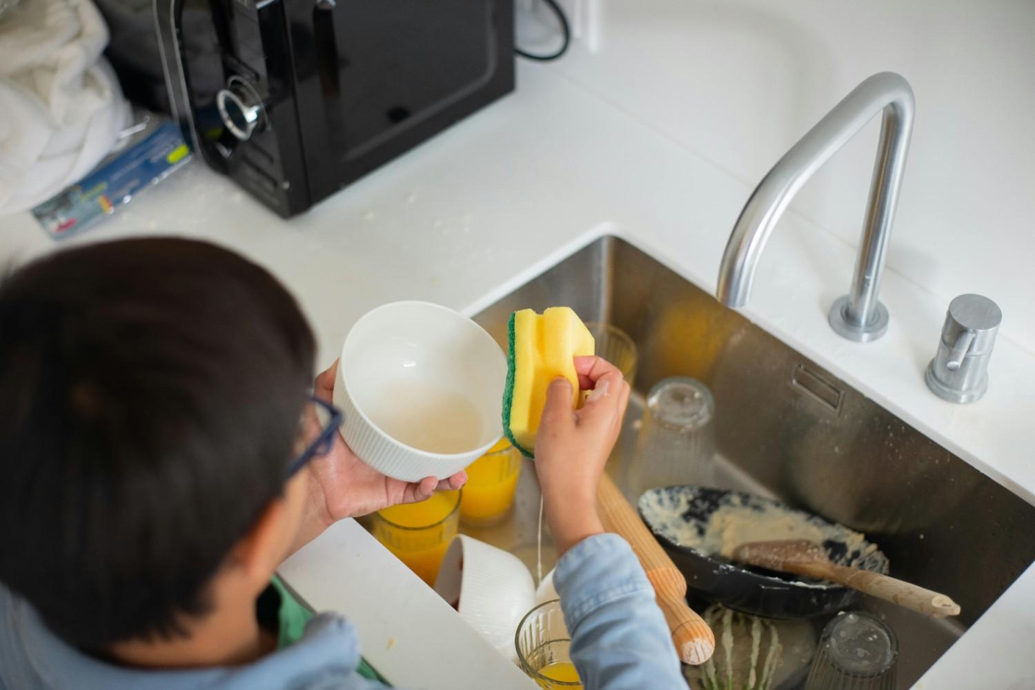 sink1 A boy washing dished in the kitchen sink